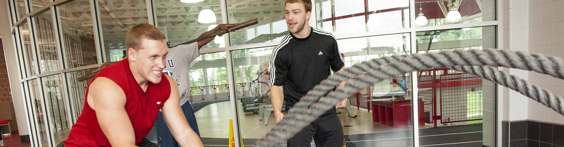 Student working out with ropes as a trainer encourages him