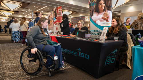 student speaking with employer at a table during an employment fair