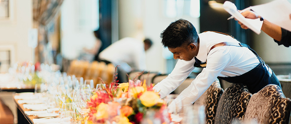 A waiter setting up a long table for an event