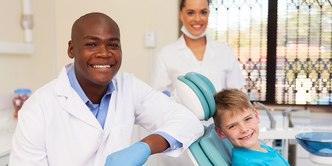 A Clinical Dental Assistant, a Dentist, and a young patient smile.