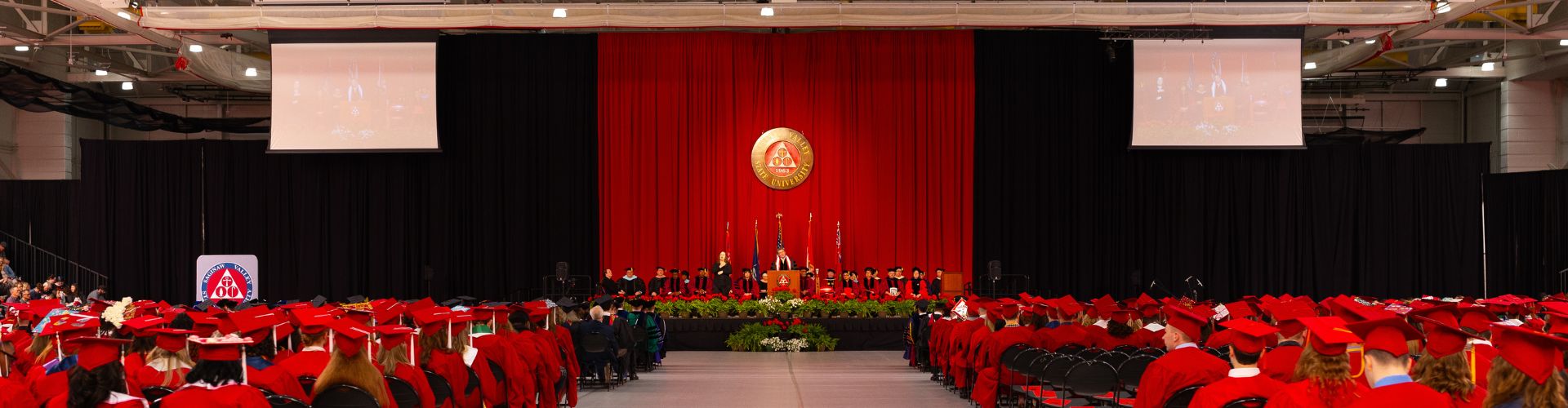 Graduating students in front of decorated commencement stage with SVSU crest