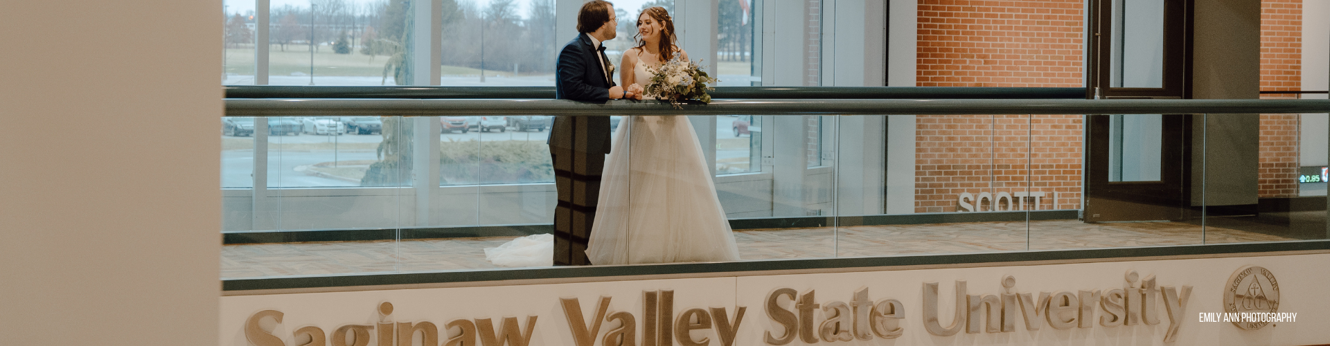 bride and groom standing against a railing with 