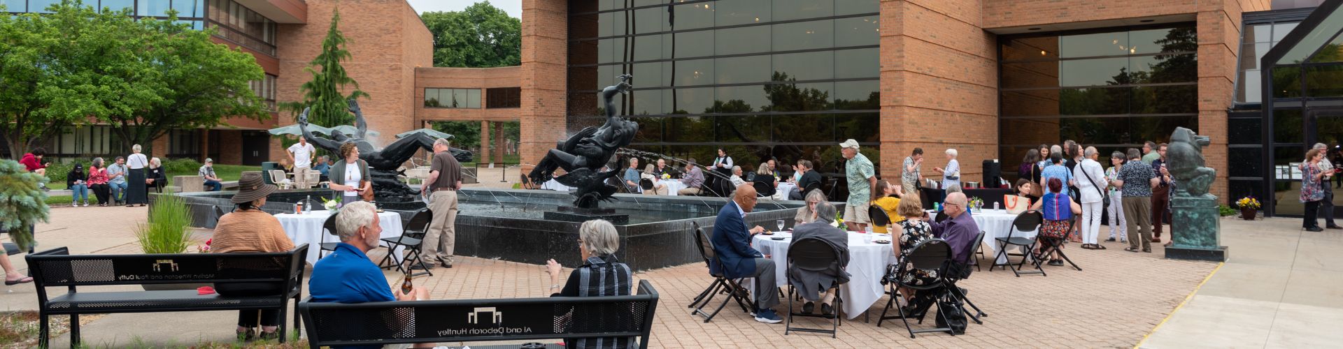 People sitting at tables around a sculptural fountain