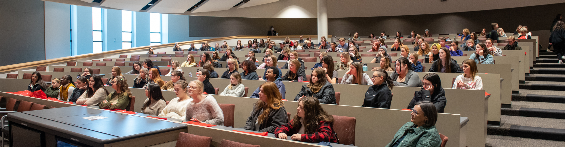 crowd sitting in tiered lecture seats