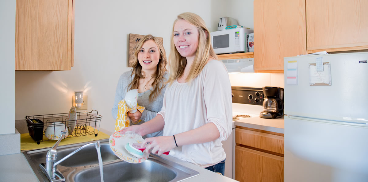 Students washing dishes in Living Center Dorm Room