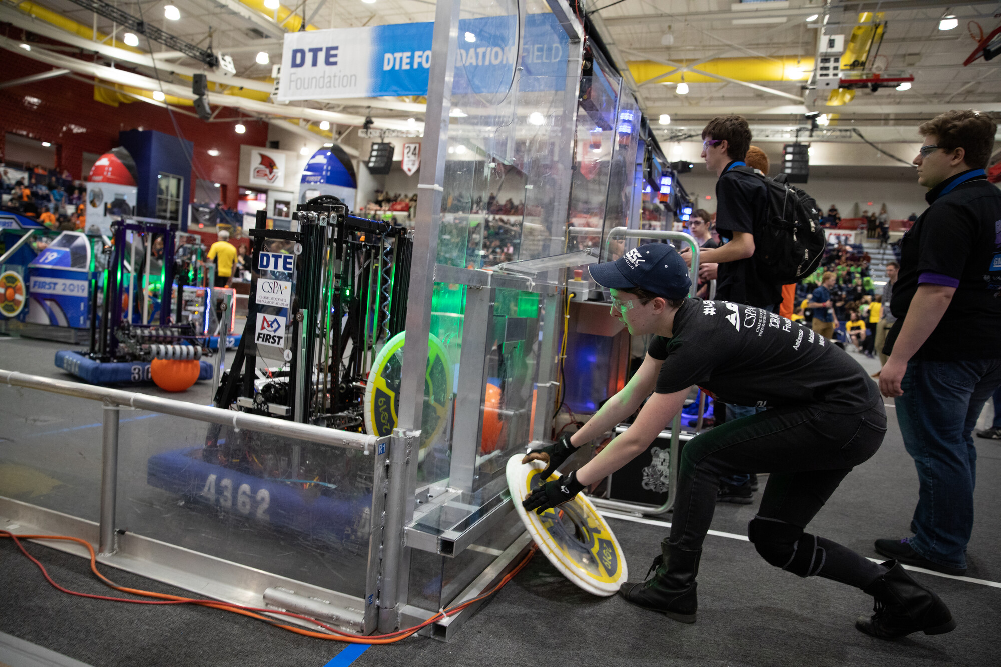 student adjusting part next to robotics competition floor