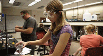 Young girl working with mentors in a chemistry lab