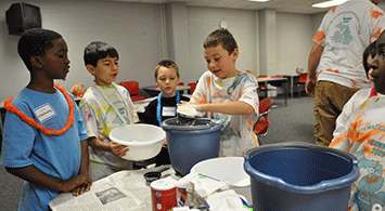 Young boys mixing ingredients in a bucket.