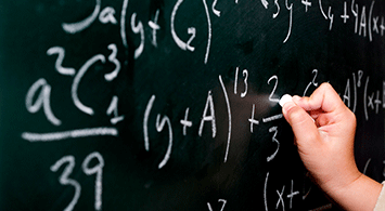 A hand writing math problems on a chalkboard.