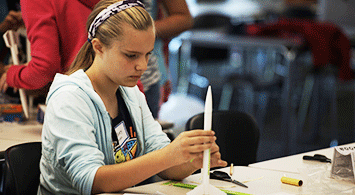 Young girl working on a model rocket.