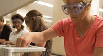 Girl working in a chemistry lab with other students.