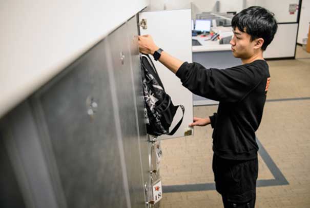 Student putting backpack in locker